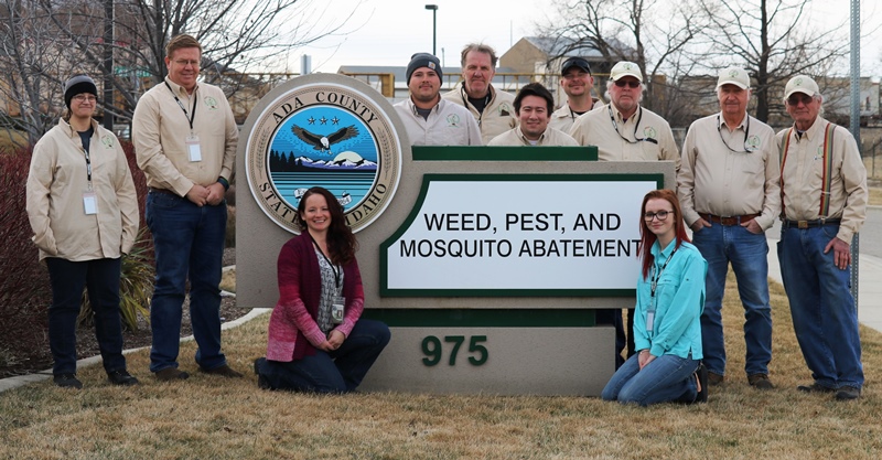 Pest Control employee's standing outside next to the sign